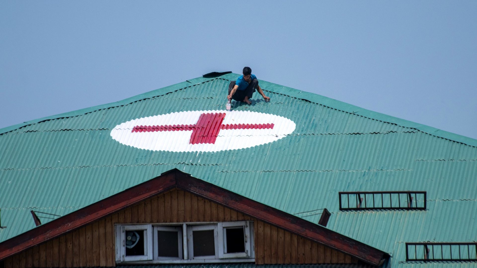 
                                A man paints a red cross on the roof of a hospital in Srinagar, Kashmir
                            