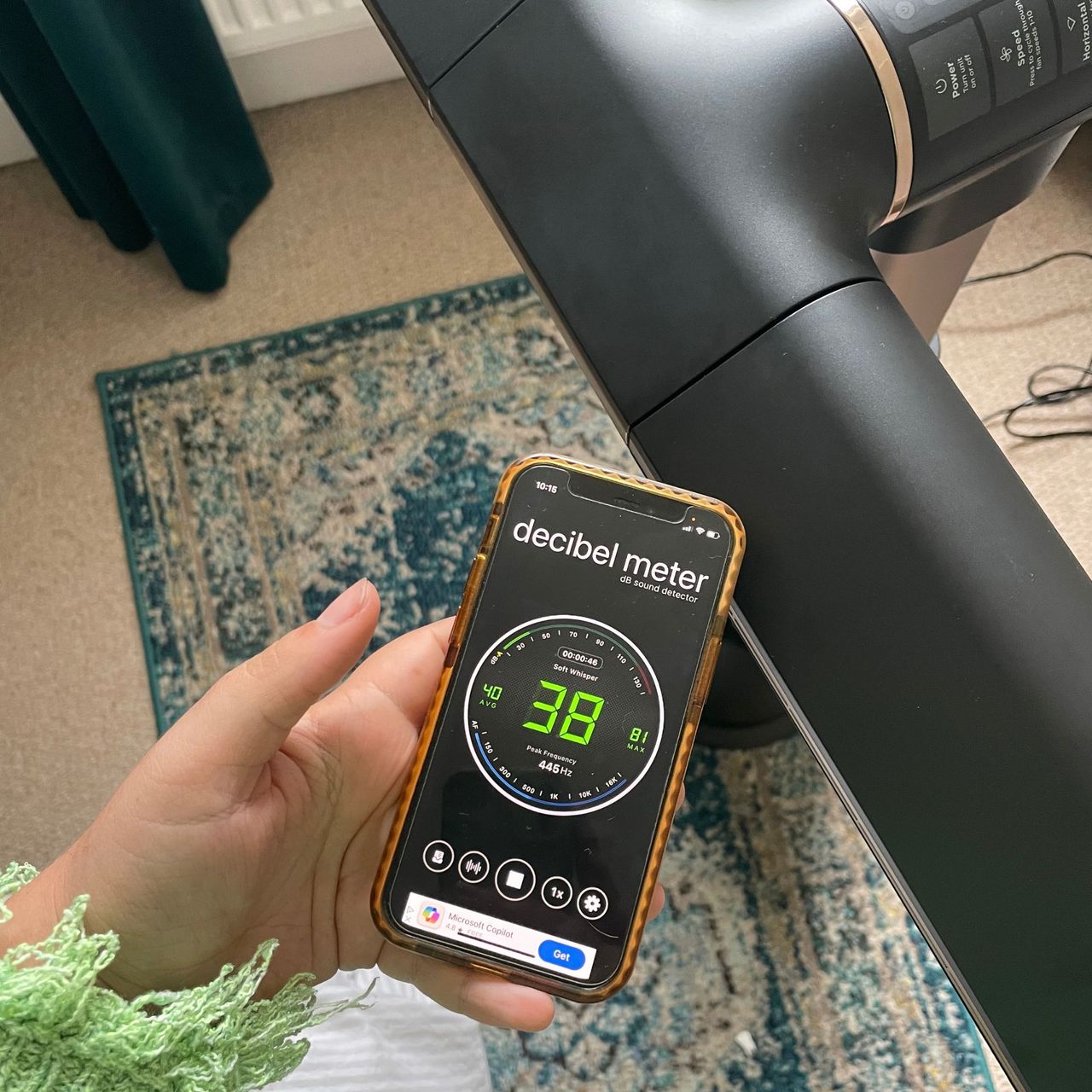 Hand holding a phone with a decibel meter on it next to the Shark TurboBlade fan