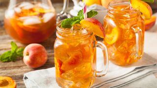 Peach ice tea in glass beakers with straw and mint garnish