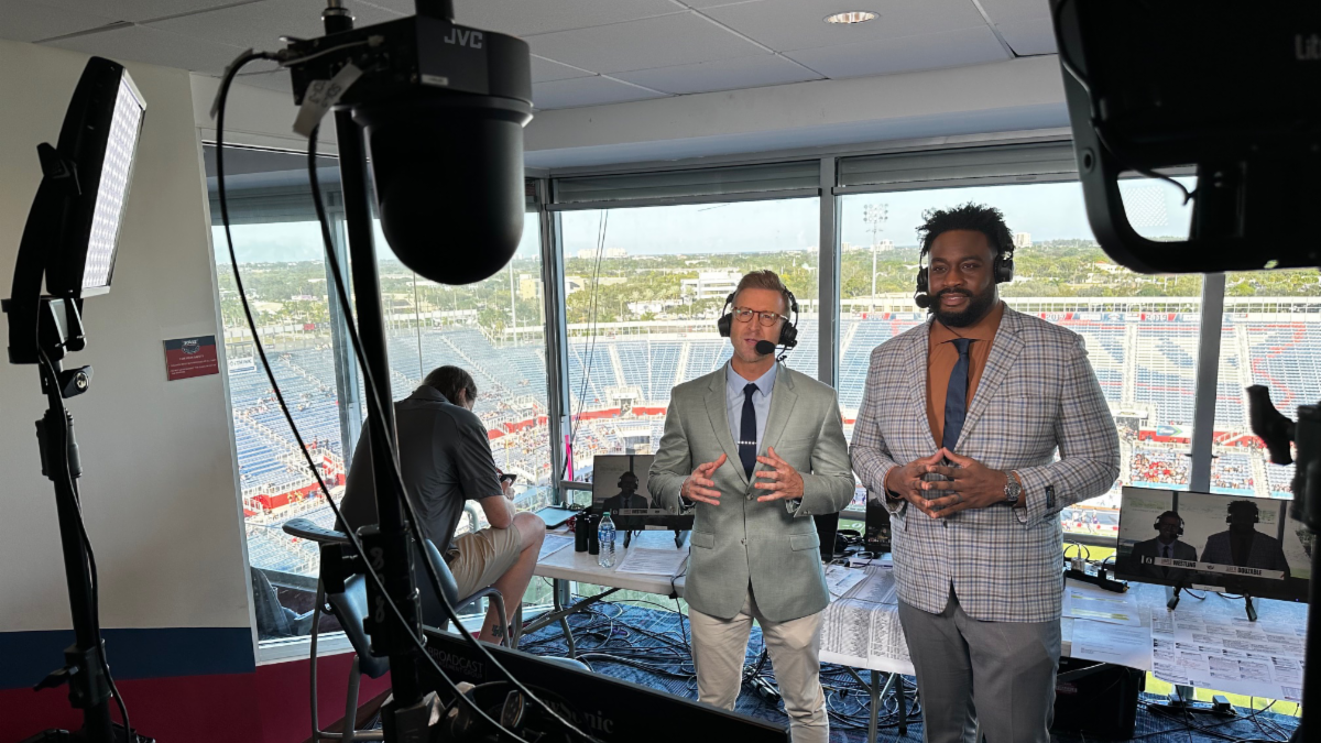 Two announcers record a pre-game preview in front of JVC PTZ cameras. 