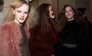 Models are seen with crimped hair, wearing fluffy marabou jackets in pink, burgundy and black