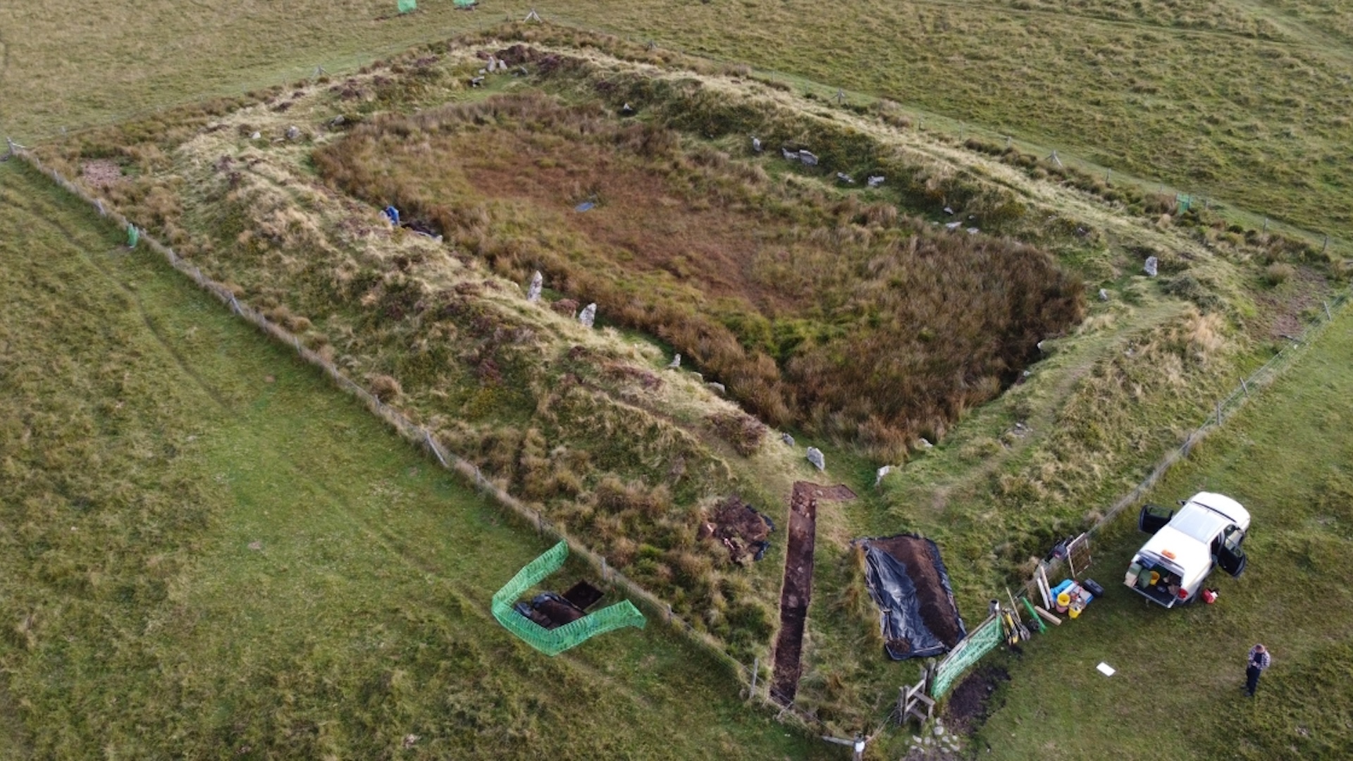 A rectangular excavation site in a grassy field