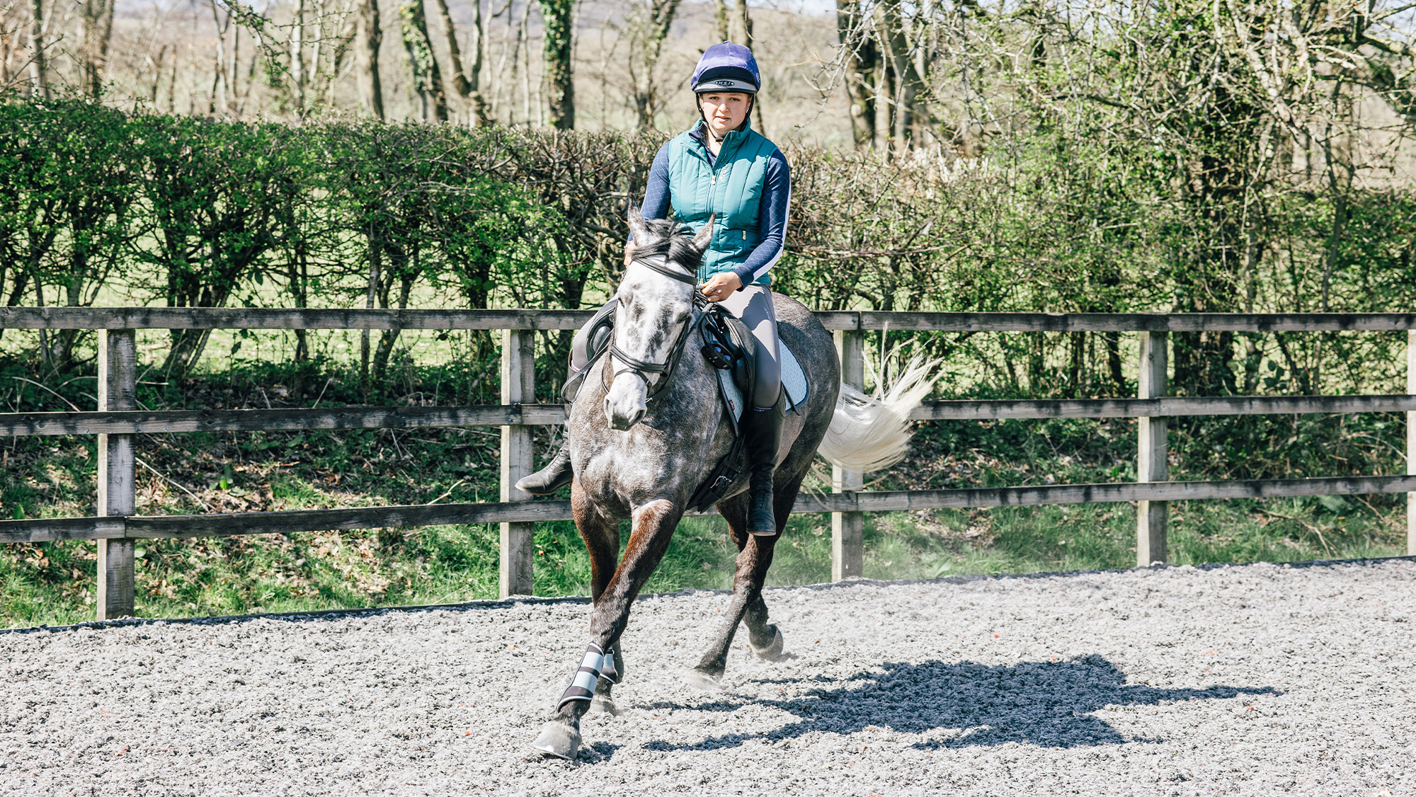 Rider cantering on circle towards camera with no stirrups