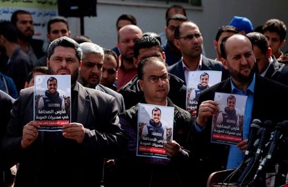Palestinian journalists carry a portrait of journalist Yasser Murtaja, during his funeral in Gaza City on April 7, 2018. 