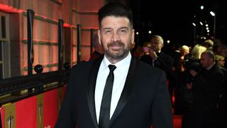 Nick Knowles at a red carpet event wearing a black suit and white shirt