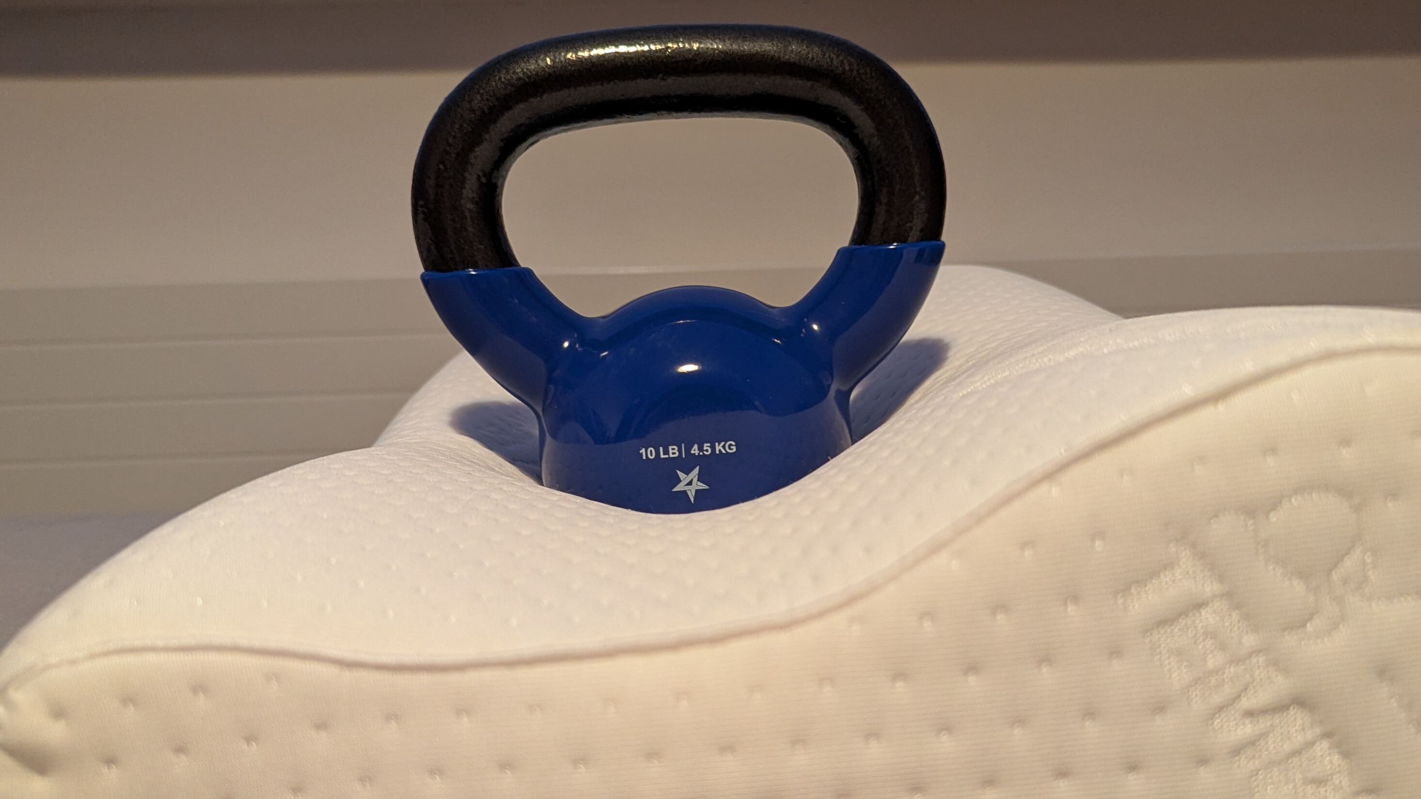 A black and blue kettlebell placed on the surface of a white curved pillow