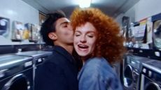 Two people kissing in a laundrette