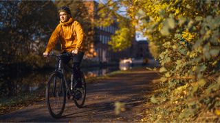 A lifestyle shot of a man riding a Ribble hybrid in a leafy environment