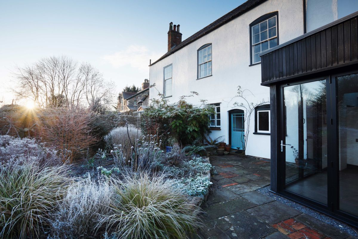 Black timber clad extension to white rendered house on frosty morning