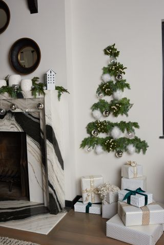 Garland DIY Christmas tree on white wall near mantel