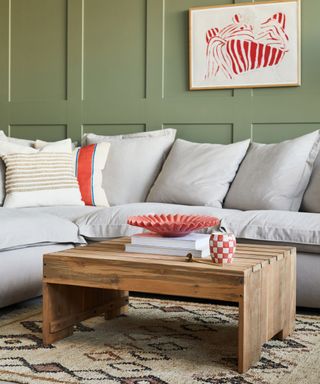 A green small living room with a gray couch and a wooden coffee table