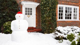 Image of a snowman in front of a house