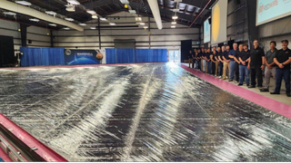 A line of NASA engineers posing with a silver solar sail.