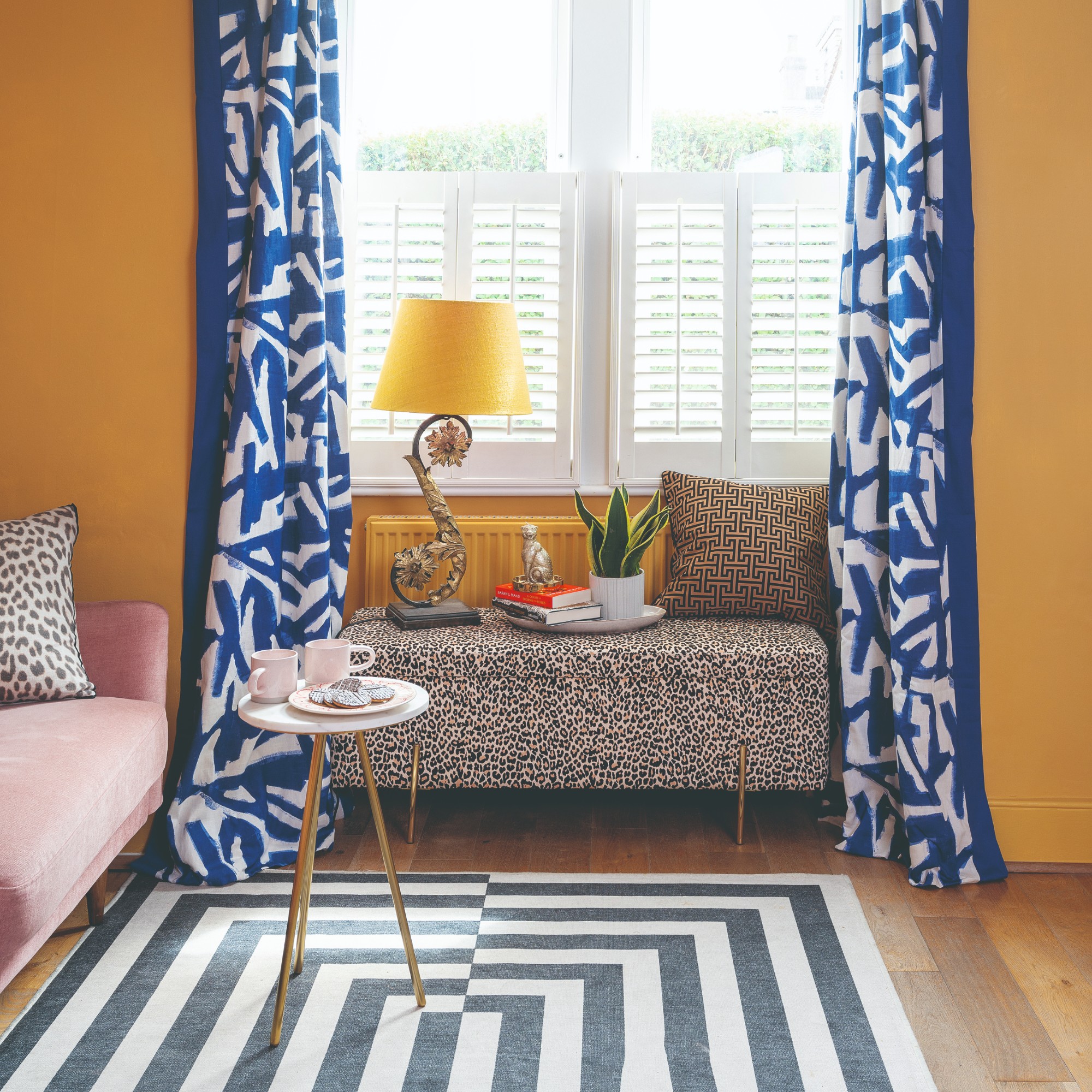 A yellow living room with a leopard-print storage window bench and a black and white graphic rug