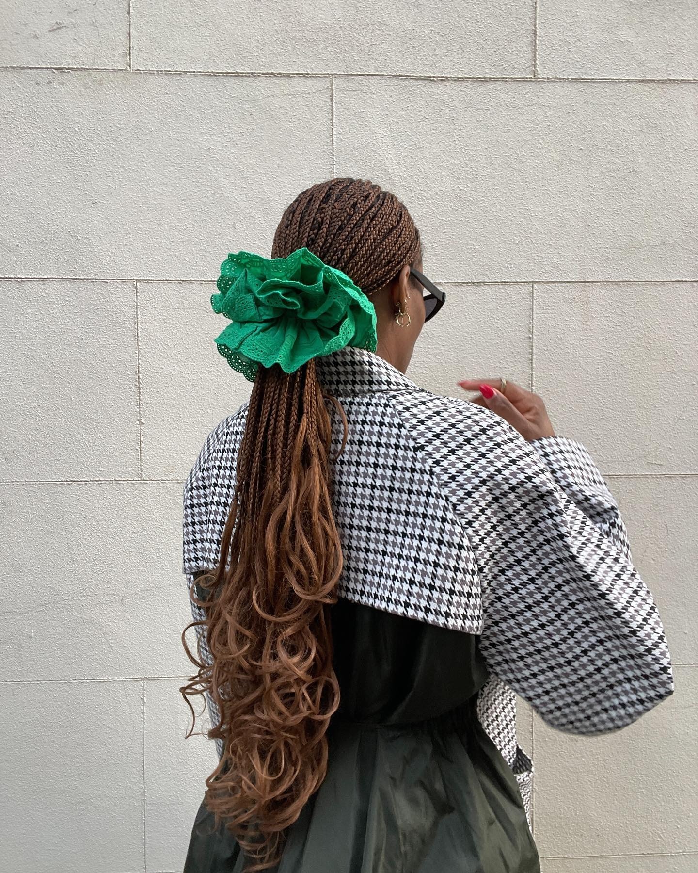 A woman with braided hair styled in a ponytail with an oversized scrunchie