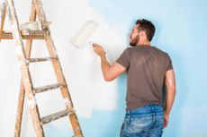 A man painting a wall with a paint roller