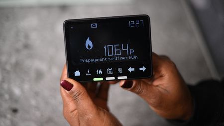 A woman shows her smart meter indicating that she is on a 'Prepayment tariff'