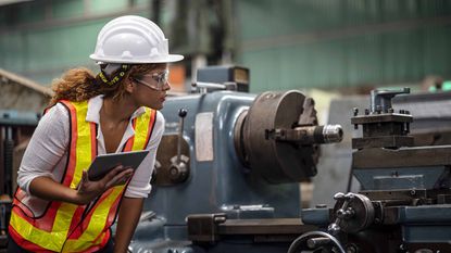 A female factory worker examines a machine