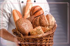 A close up of a chef holding a basket of different varieties of bread