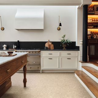 White kitchen with stainless steel oven, wooden island and stone effect LVT flooring