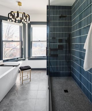 Bathroom decorated with dark blue shower tiles on the wall and gray stone tiles on the floor