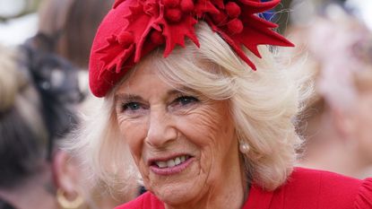Queen Camilla’s bright red tunic dress worn as she meets guests after a ceremony