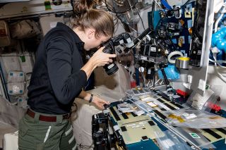 NASA astronaut Kayla Barron, seen photographing an experiment, set up the squares for SQuARE by the International Space Station Archaeological Project.