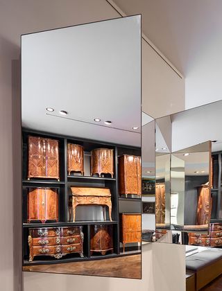 Mirrors showing a selection of glossy wooden cupboards and drawers on show in a modular display cabinet
