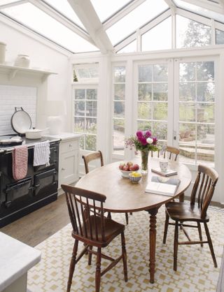 Kitchen dining room with black aga wooden tables and chairs with flowers in the centre