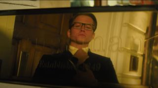 Taron Egerton adjusts his tie with his reflection in Kingsman: The Golden Circle.
