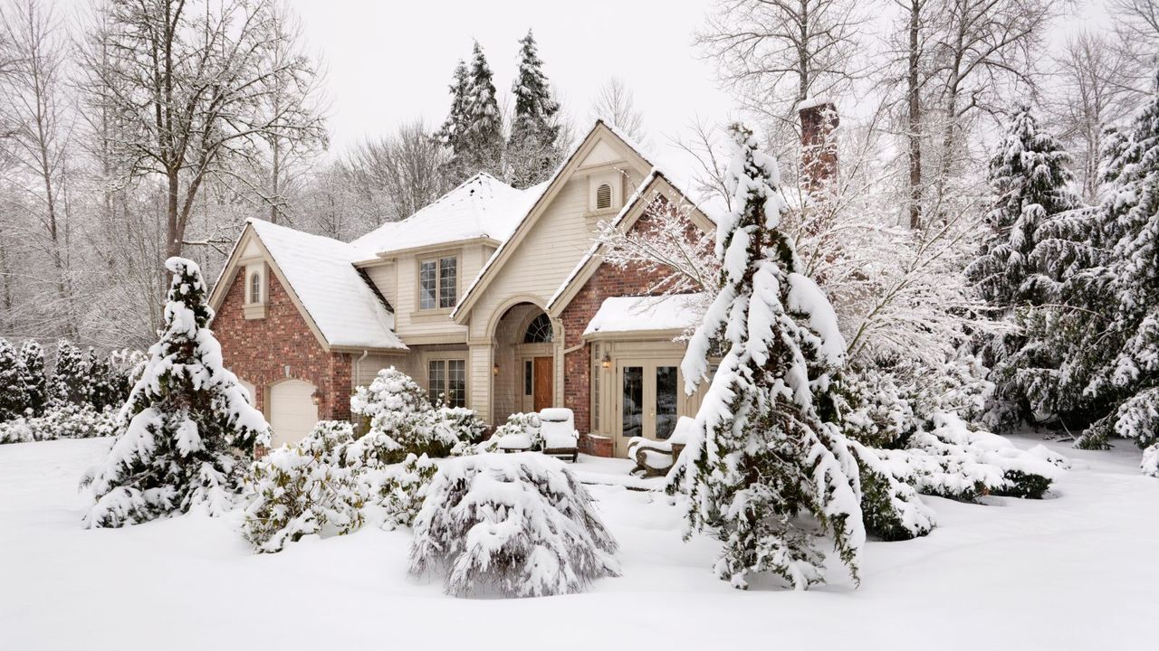 Suburban house with snow on the ground and more falling