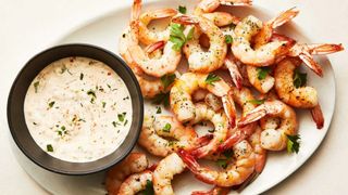 overhead shot of an oval platter with roasted shrimp and a bowl of horseradish sauce