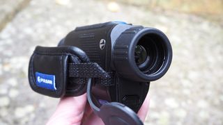 Pulsar Axion XQ30 PRO night vision monocular held in a hand over a stone surface