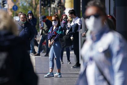 People wearing protective face masks wait for a street tram on April 20, 2020 in Leipzig, Germany