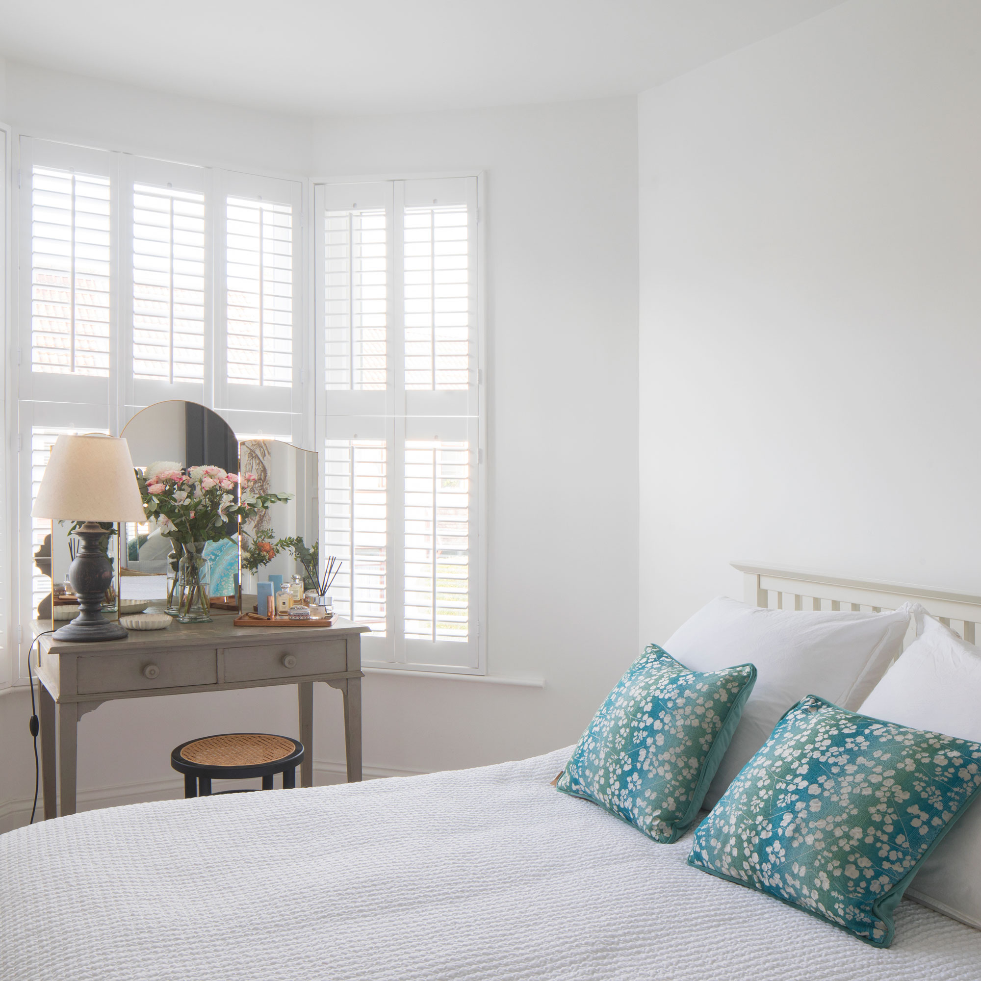 White guest bedroom with a grey dressing table and blue cushions