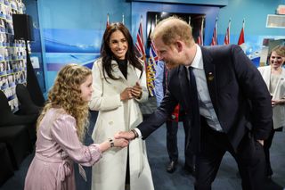 Meghan Markle kisses Prince Harry while wearing a cream alpaca coat, and meets a young girl at the Invictus Games 2025 in Canada