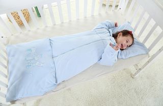 Baby girl lying in bed wearing a baby sleeping bag