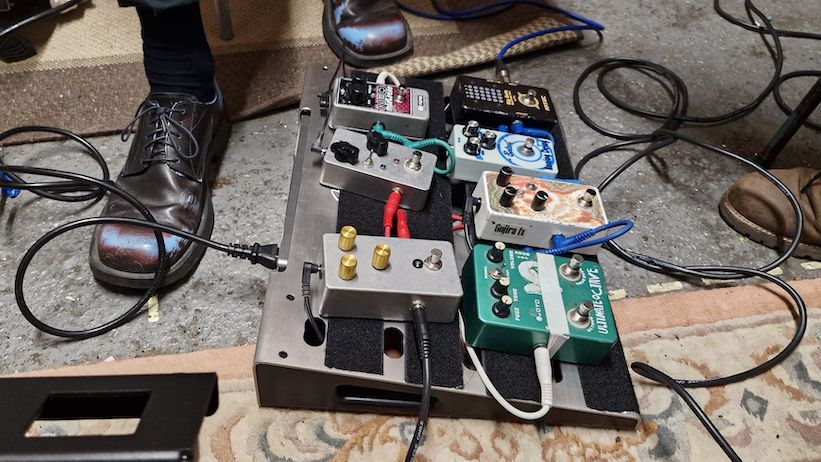 A Fender Professional Small pedalboard with pedals on a rehearsal room floor