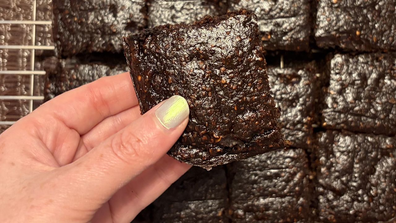 A close up of a hand holding a brownie