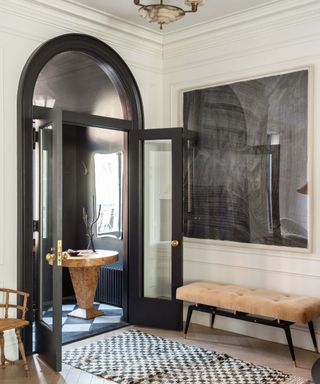 Beige hallways with black arched doorway and checkerboard rug