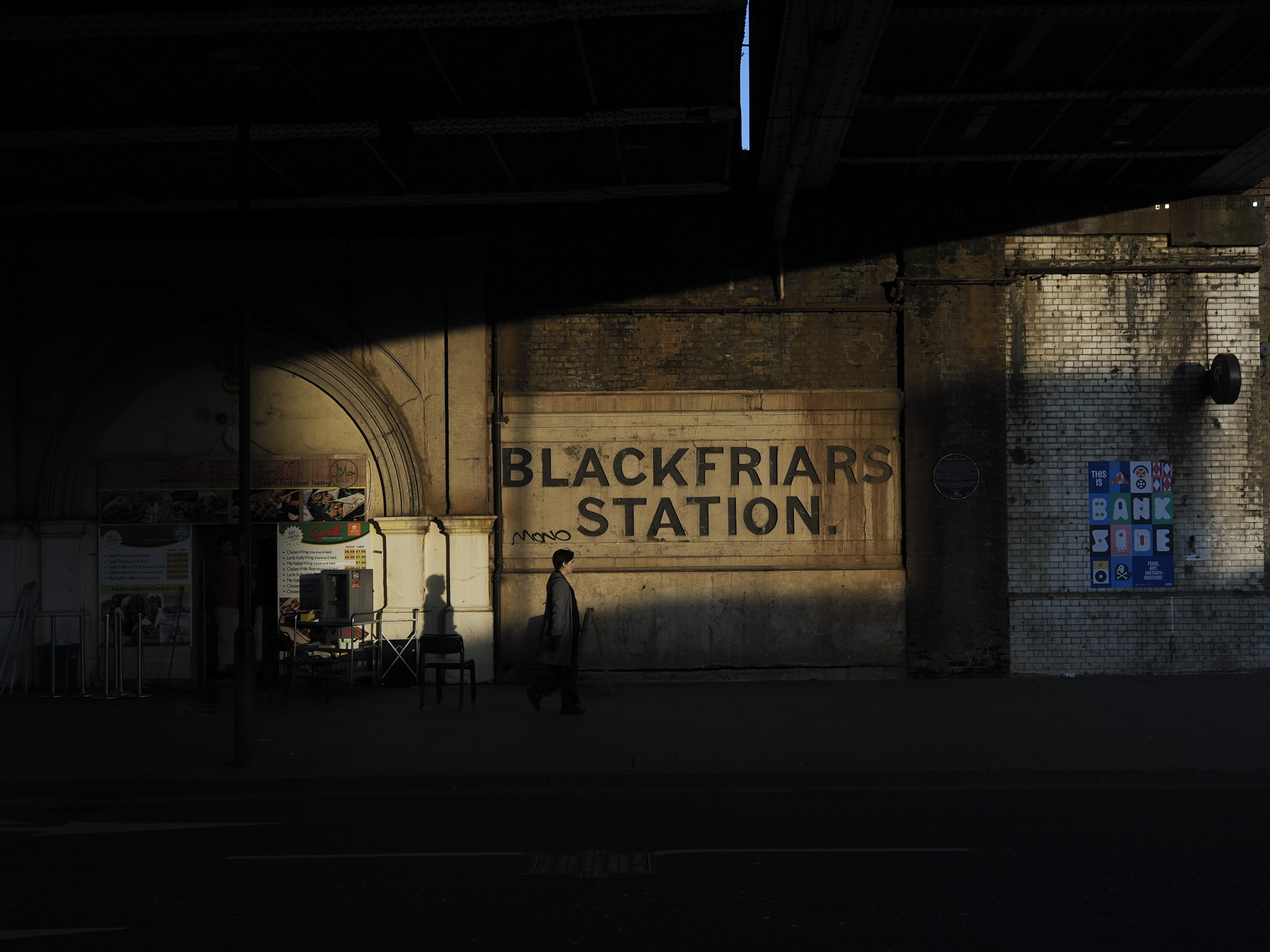 OM System OM-3 sample photos: London underpass with a shaft of light illuminating the old wall and passerby