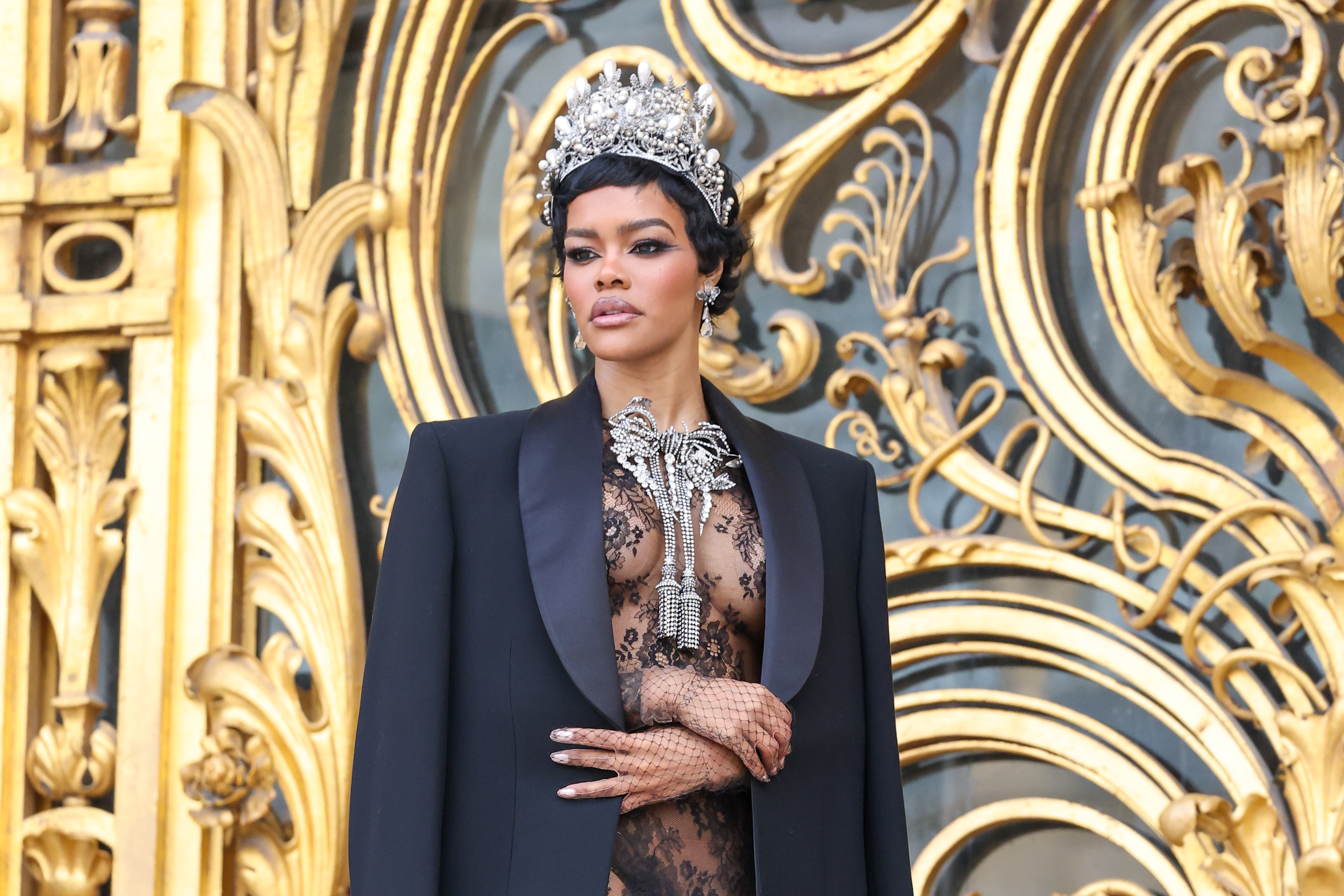 Teyana Taylor arrived at the Schiaparelli couture show in a lace little black dress, a crown, and a bow necklace inspired by her golden globes back
