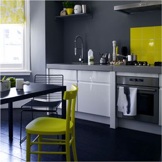 kitchen with black wall and flooring white cabinet with kitchen hood and dinning table with chair