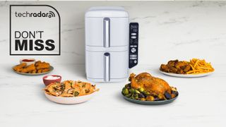 A white Ninja Double Stack XXXL air fryer on a kitchen counter, surrounded by plates of cooked food.