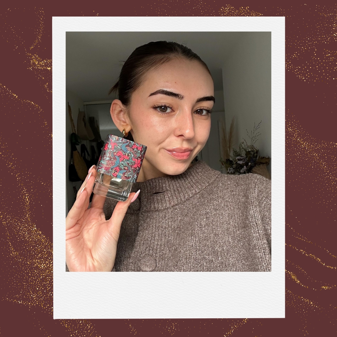 A picture of Digital Beauty Writer, Sennen Prickett, holding a bottle of the Liberty LBTY. Fragrance Zephirine Eau de Parfum/ in a burgundy template with a gold glitter overlay