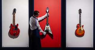 An auctioneer hold's Noel Gallagher's Flying V before auction at Sotheby's