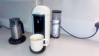 White Nespresso Vertuo machine with a cream mug on the cup holder in a kitchen.