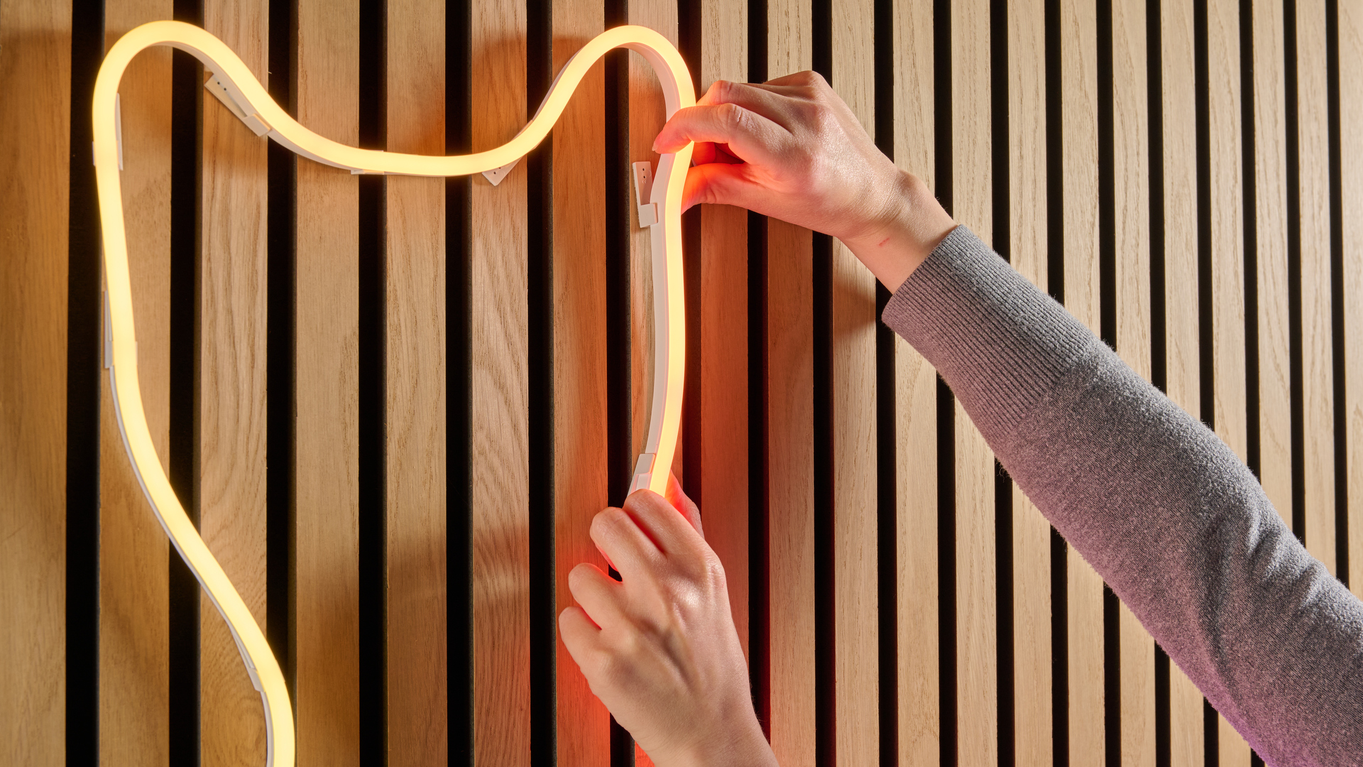 A woman is adjusting the Nanoleaf rope light.