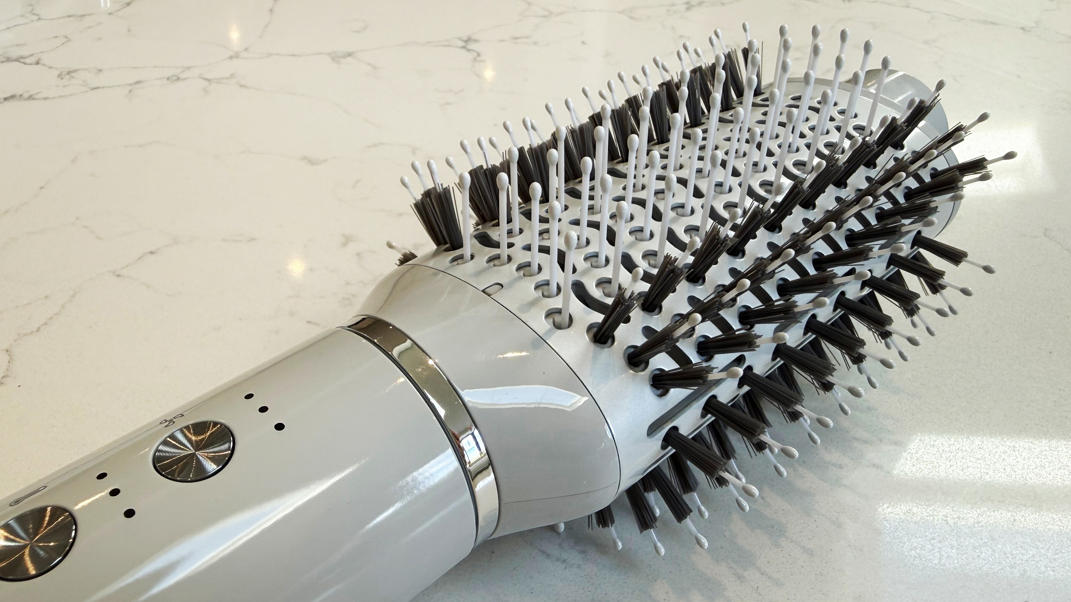 Close-up of the T3 Aire 360 oval brush attachment, showing the mixed SmoothGrip bristles and white-tipped pins on the CeraGloss ceramic surface