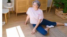 woman does a seated hip stretch on floor